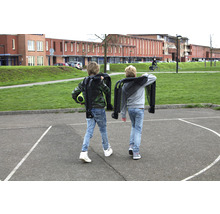 Dvě děti nesou složené vozíky na školním dvoře.