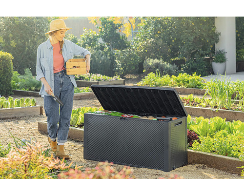 Zahradní scéna s ženou držící bednu na nářadí a otevřeným úložným boxem na zahradu