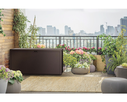 Exteriér terasy s hnědým úložným boxem, rostlinami a výhledem na město