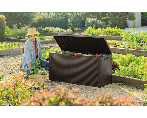 Zahradní scéna se ženou pracující v blízkosti otevřeného hnědého zahradního boxu