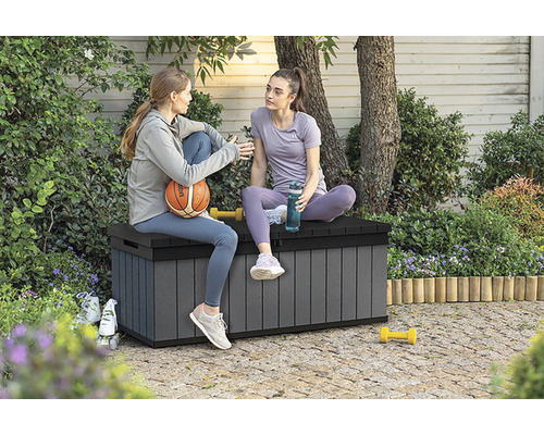 Dvě ženy sedí venku na šedé zahradní truhle
