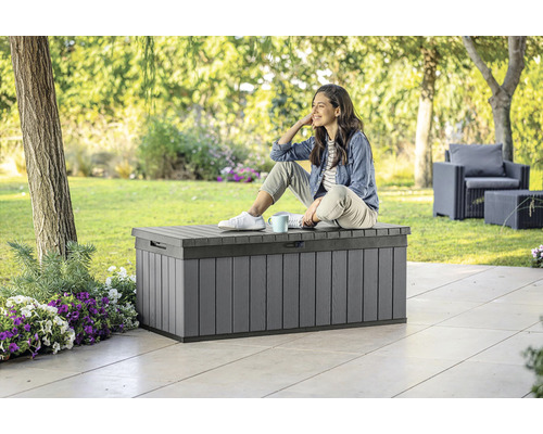 Šedá zahradní bedna venku se sedící ženou