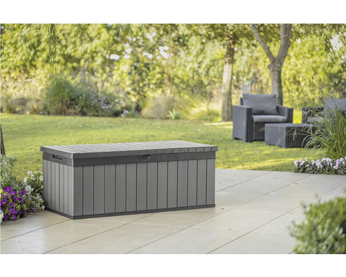 Fotografie šedé zahradní bedny na terase, se zahradním nábytkem a stromy v pozadí.