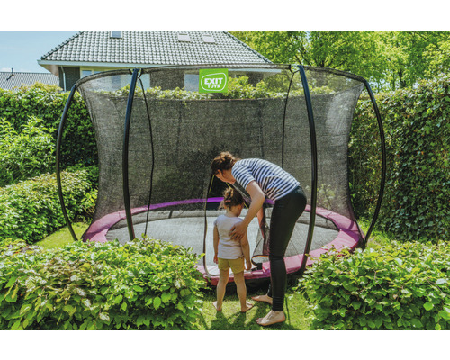 Zahradní scéna s trampolínou s ochrannou sítí, ženou a dítětem.