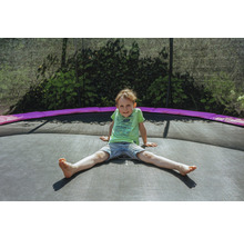 Chlapec sedí na zahradní trampolíně s bezpečnostní sítí.