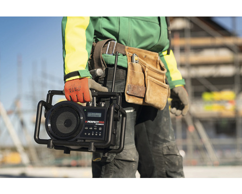 Řemeslník drží staveništní rádio značky Perfectpro.