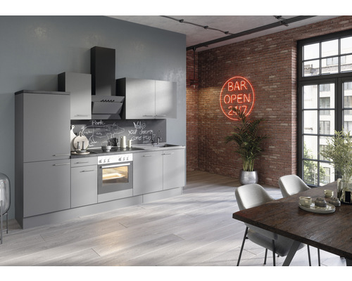 Moderní kuchyně se šedými skříněmi, digestoří a jídelním stolem v loftovém prostoru s cihlovou zdí.