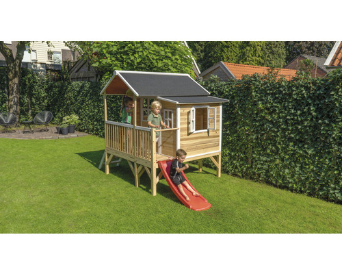 Dřevěný hrací domek se skluzavkou na zahradě s hrajícími si dětmi
