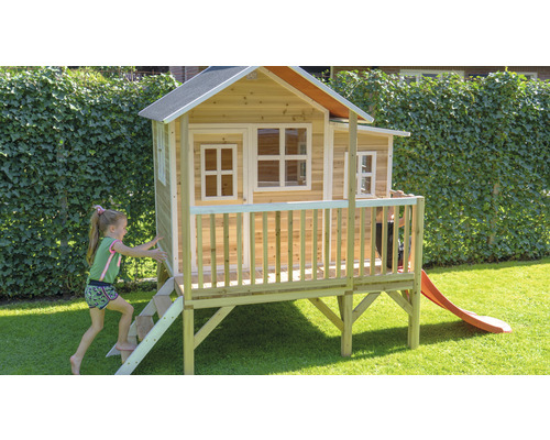 Dřevěný hrací domek se skluzavkou a schody na zahradě