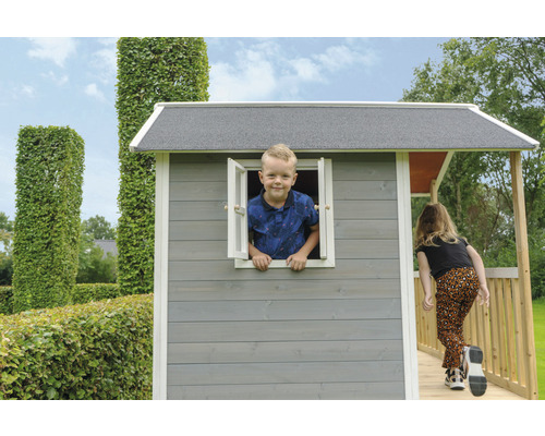 Dítě si hraje v šedém dřevěném hracím domku s rampou a oknem