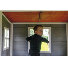 Dítě stojí v dřevěném hracím domku s okny