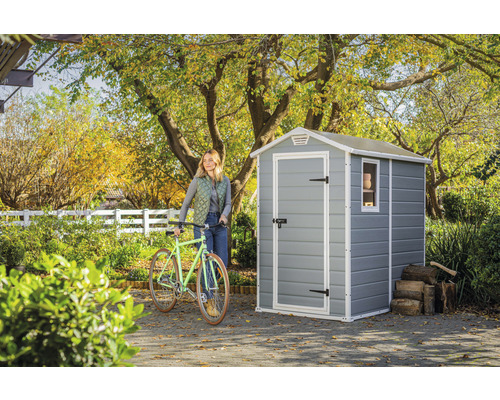 Zahradní scéna se zahradním domkem, jízdním kolem a ženou na zahradě