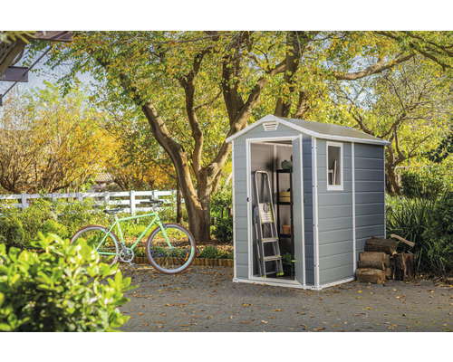 Zahradní scéna s kůlnou na nářadí, kolem, žebříkem, regálem a hromadou dřeva