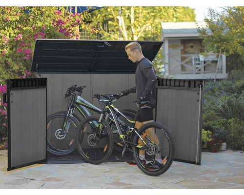 Plastový box na kola se dvěma jízdními koly a jednou osobou na zahradě