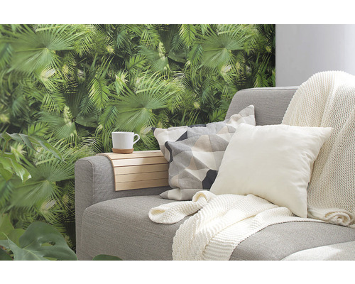 Šedá pohovka s polštáři, držákem na pití a tropickou fototapetou