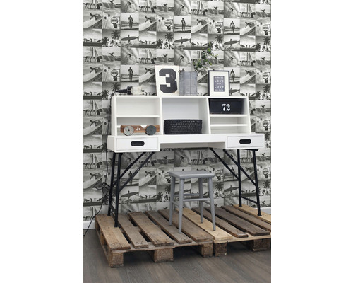 Psací stůl s policemi, židle a dekorace na paletách před fototapetou s plážovými motivy.