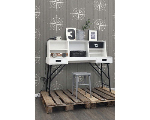 Pracovna s bílým psacím stolem, šedou židlí a dřevěnou paletovou podlahou před tapetou se vzorem kompasu