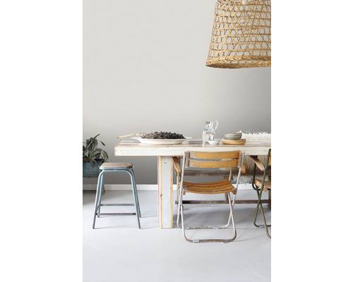 Jídelní stůl se židlemi a závěsnou lampou z ratanu.