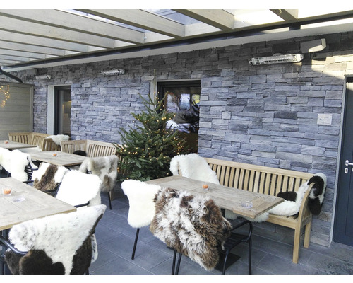 Venkovní posezení se stoly, lavicemi, židlemi s kožešinou a malým vánočním stromkem.