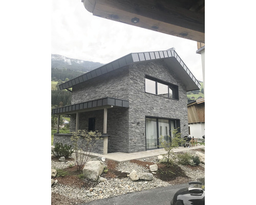 Fasáda domu s obkladem z přírodního kamene, okna a dveře