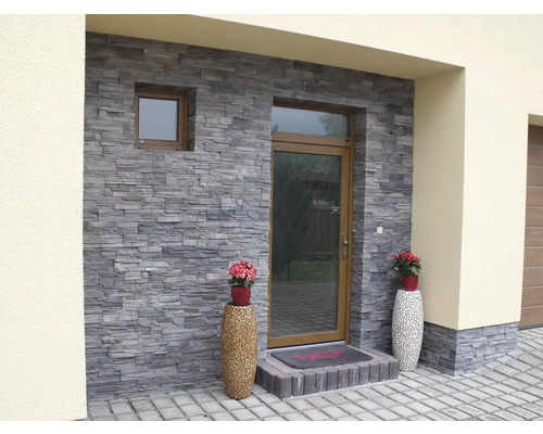 Exteriér domu s kamenným obkladem na fasádě a ozdobnými květináči.