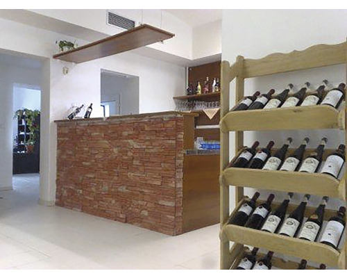 Interiérová fotografie baru s víny v regálu a kamenným pultem