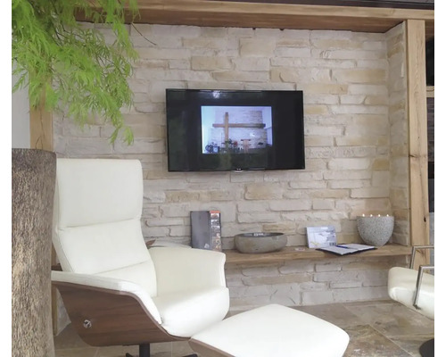 Obývací pokoj s křeslem, televizí a kamennou zdí