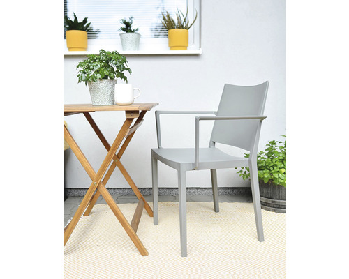 Scéna s dřevěným stolem, šedým křeslem a pokojovými rostlinami na balkóně