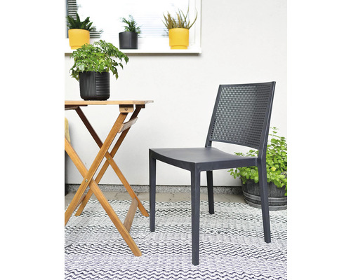 Zahradní scéna s dřevěným stolem, plastovou židlí a rostlinami na koberci