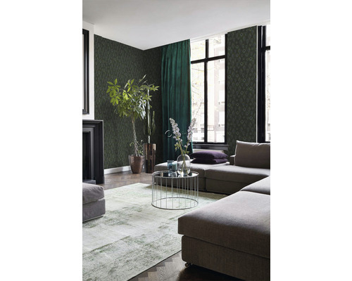 Obývací pokoj se zelenou vzorovanou tapetou, šedou modulární pohovkou, kulatým konferenčním stolkem a pokojovými rostlinami