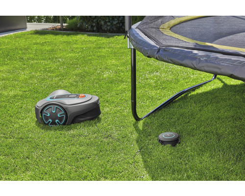 Robotická sekačka Gardena s nabíjecí stanicí na trávníku pod trampolínou
