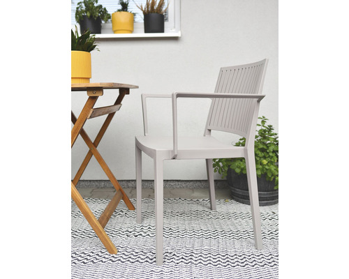 Zahradní scéna s křeslem, dřevěným stolem a vzorovaným kobercem