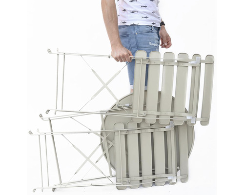 Složenou zahradní soupravu stolu a židlí nese osoba.