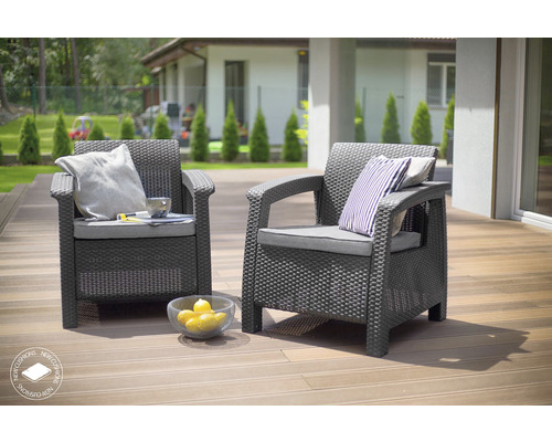 Dvě šedá proutěná křesla s polštáři na terase.