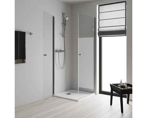 Sprchový kout se skleněnými dveřmi, sprchová armatura a držák na ručníky ve světlé koupelně