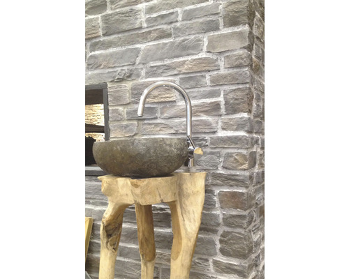 Umyvadlo z kamene na dřevěném stojanu s baterií před kamennou zdí