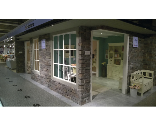 Výstavní prostor s kamennou zdí a okny ve venkovském stylu