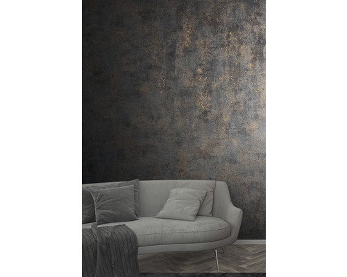 Obývací pokoj s šedou pohovkou a tmavou strukturovanou tapetou se zlatými akcenty.