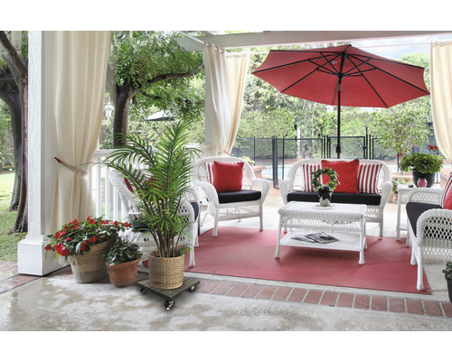 Terasa s bílým proutěným nábytkem, červeným slunečníkem a hrnkovými rostlinami
