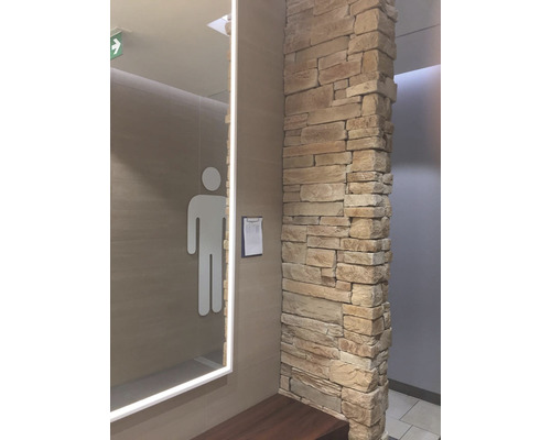 Pánské toalety se zrcadlem, piktogramem a kamennou zdí