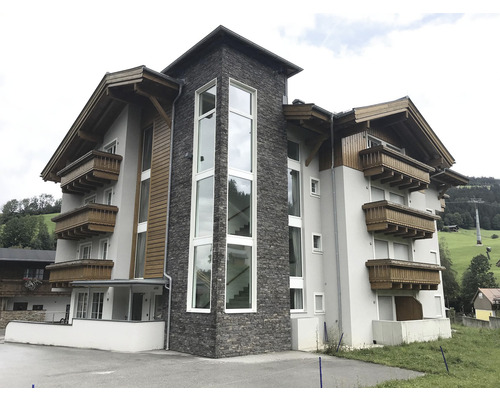 Vnější pohled na vícepatrovou budovu s balkony a kamenným obkladem