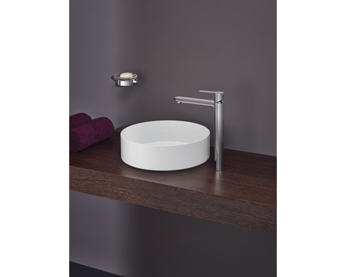 Koupelnové umyvadlo s baterií, mýdlenkou a ručníky na dřevěné polici.