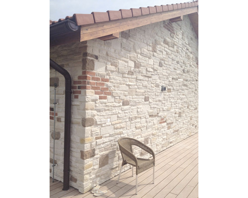 Stěna domu s obkladovými kameny a křeslem na terase