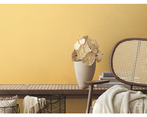 Obývací pokoj se žlutou stěnou, lavice s ratanovým pletivem, anturie ve váze a ratanová židle