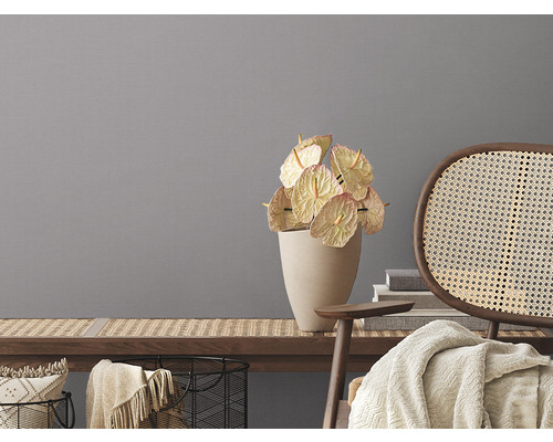 Dekorativní zátiší s anturiemi ve váze a ratanovou židlí