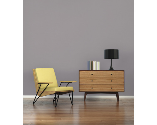 Obývací pokoj s křeslem, komodou, lampou a knihami na dřevěné podlaze