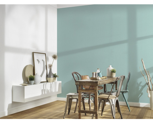 Jídelna s dřevěným stolem, židlemi a nástěnnou policí s dekoracemi před barevnou stěnou