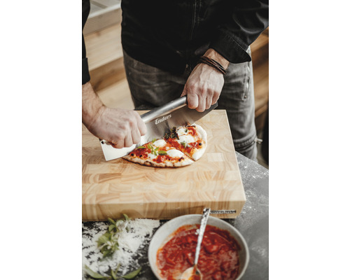 Osoba krájí pizzu na dřevěném prkénku pomocí kráječe na pizzu značky Enders.