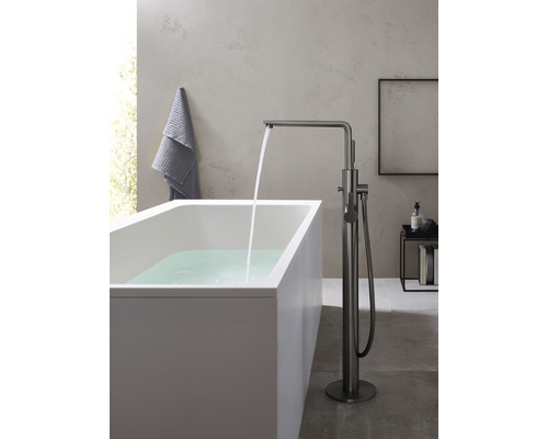 Volně stojící vana s vodovodní baterií a tekoucí vodou v koupelně