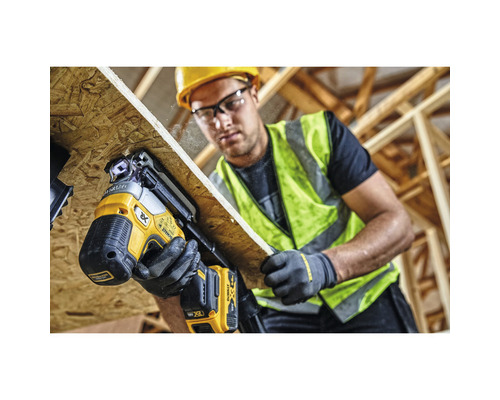 Řemeslník upevňuje dřevěnou desku pomocí akumulátorové hřebíkovačky DeWalt